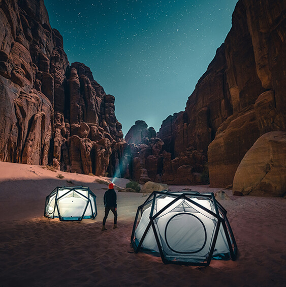 Row of illuminated tents pitched under a starry night sky in a grassy field, part of Elysium’s Instagram showcase.