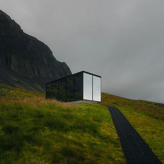 Modern cabin nestled among trees with warm interior lights seen through large windows, linking to Elysium’s Instagram.
