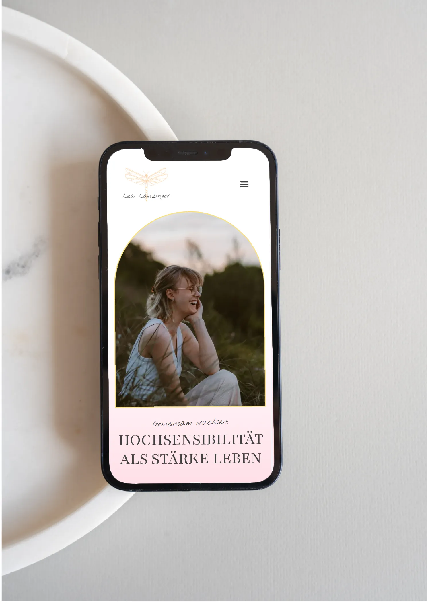 Smartphone auf minimalistischem Hintergrund mit Mockup der Website von Lea Lanzinger