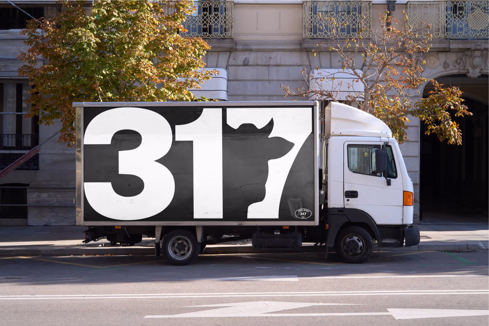 Delivery truck with a large 317 logo applied to its side, parked in front of a warehouse.