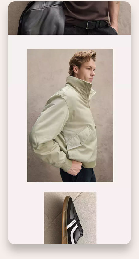 Side profile of a young man wearing a light beige bomber jacket with a high collar and large buttoned flap pockets, standing against a plain textured wall.