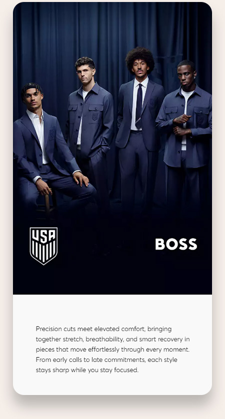 Four male models wearing sharp, navy-colored suits and jackets standing in front of a dark blue curtain backdrop, with a USA Soccer crest and the word BOSS visible below them.