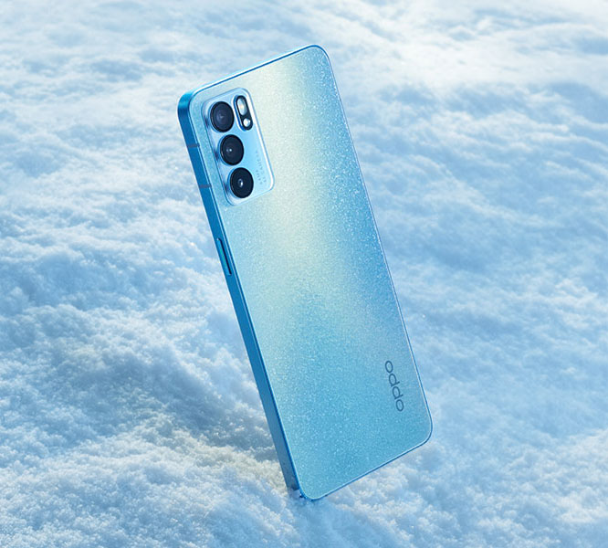 Blue OPPO smartphone with triple rear cameras standing upright on a textured snow surface with a light sparkling finish on the phone's back.