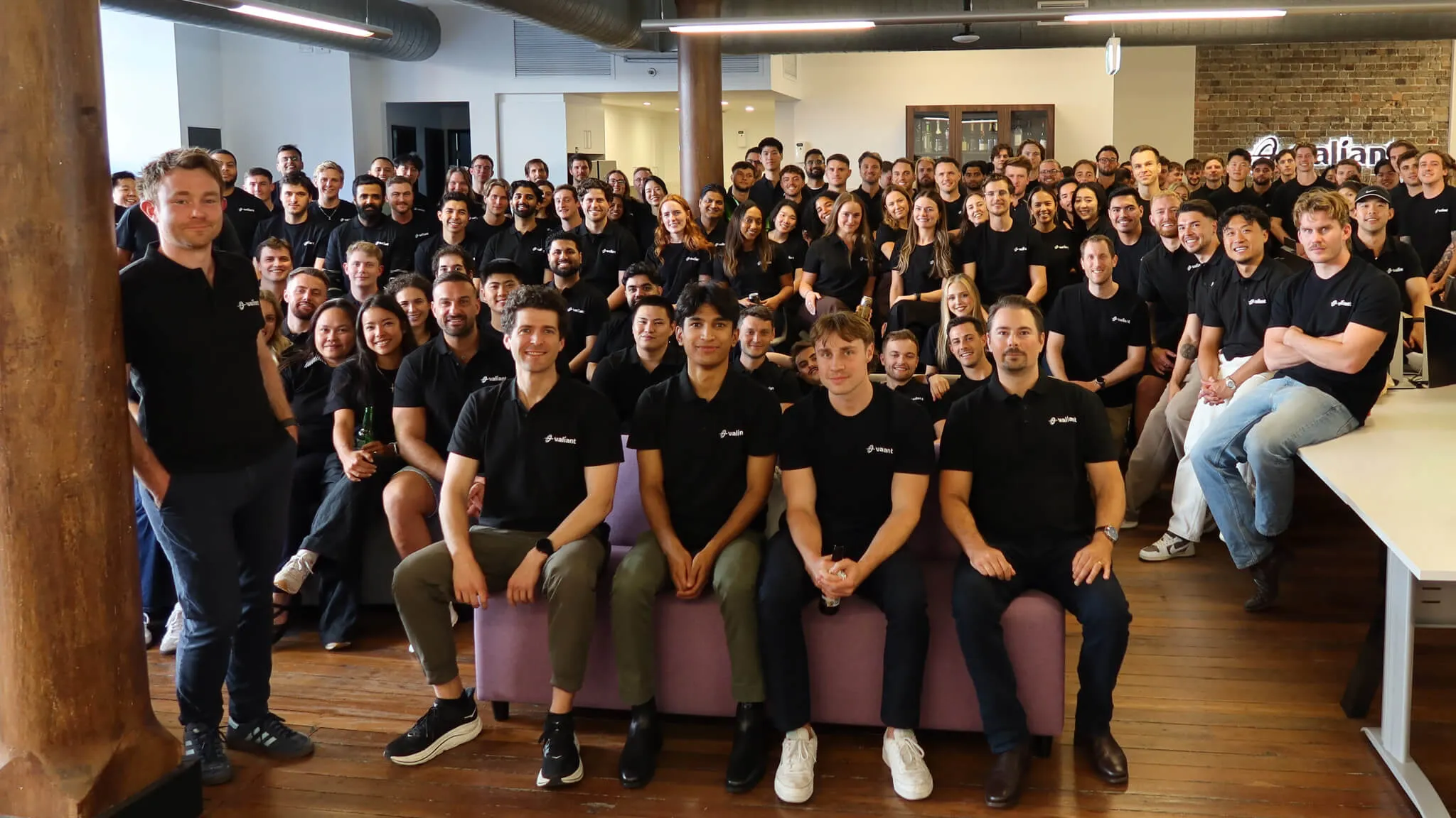 The Valiant team gathered together in the office, wearing black Valiant shirts