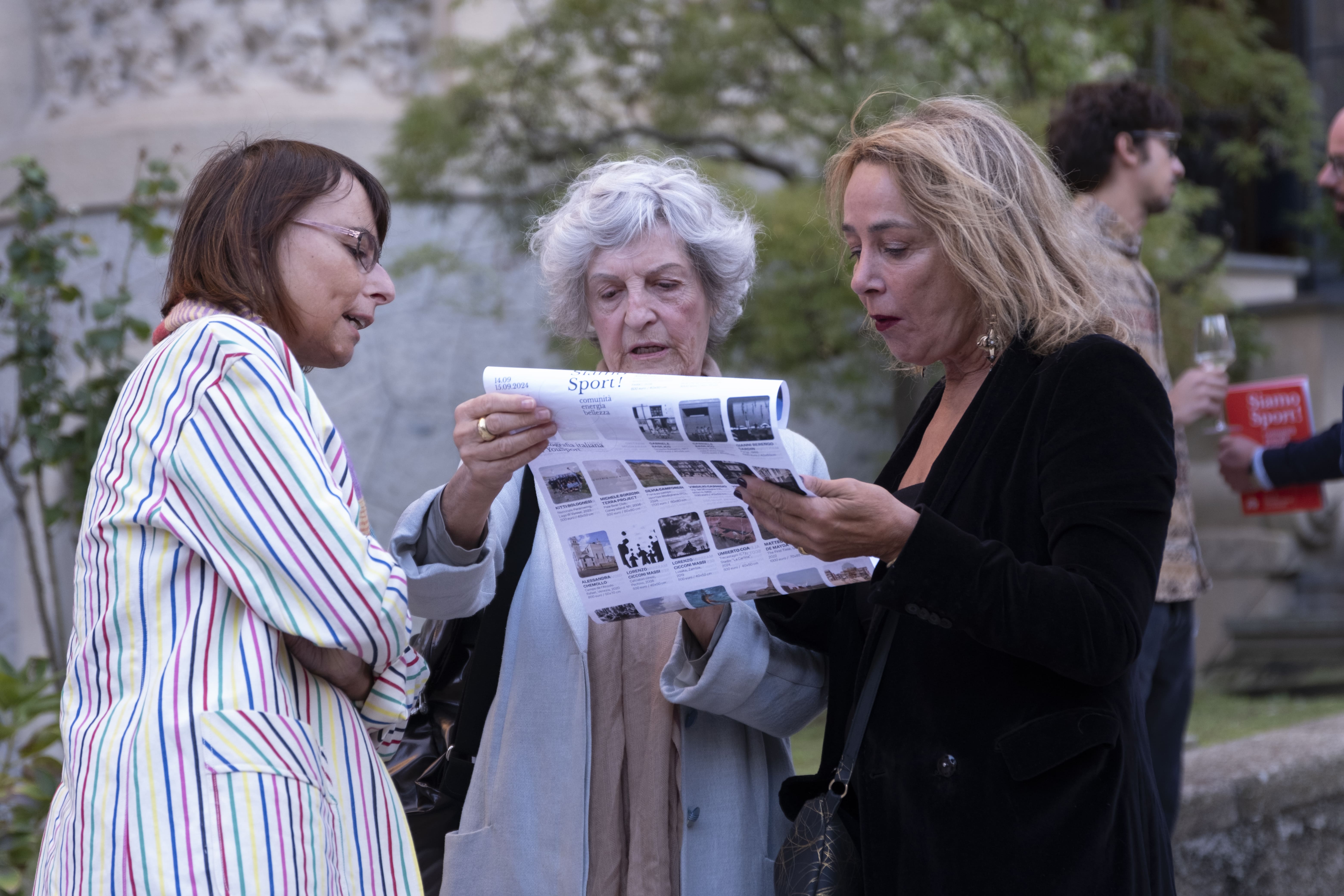 Gruppo di persone che partecipano a una corsa indossando magliette arancioni con scritte You Sport, alcune fanno il segno della vittoria e tengono uno striscione con la scritta 'Diversity is our normal'.