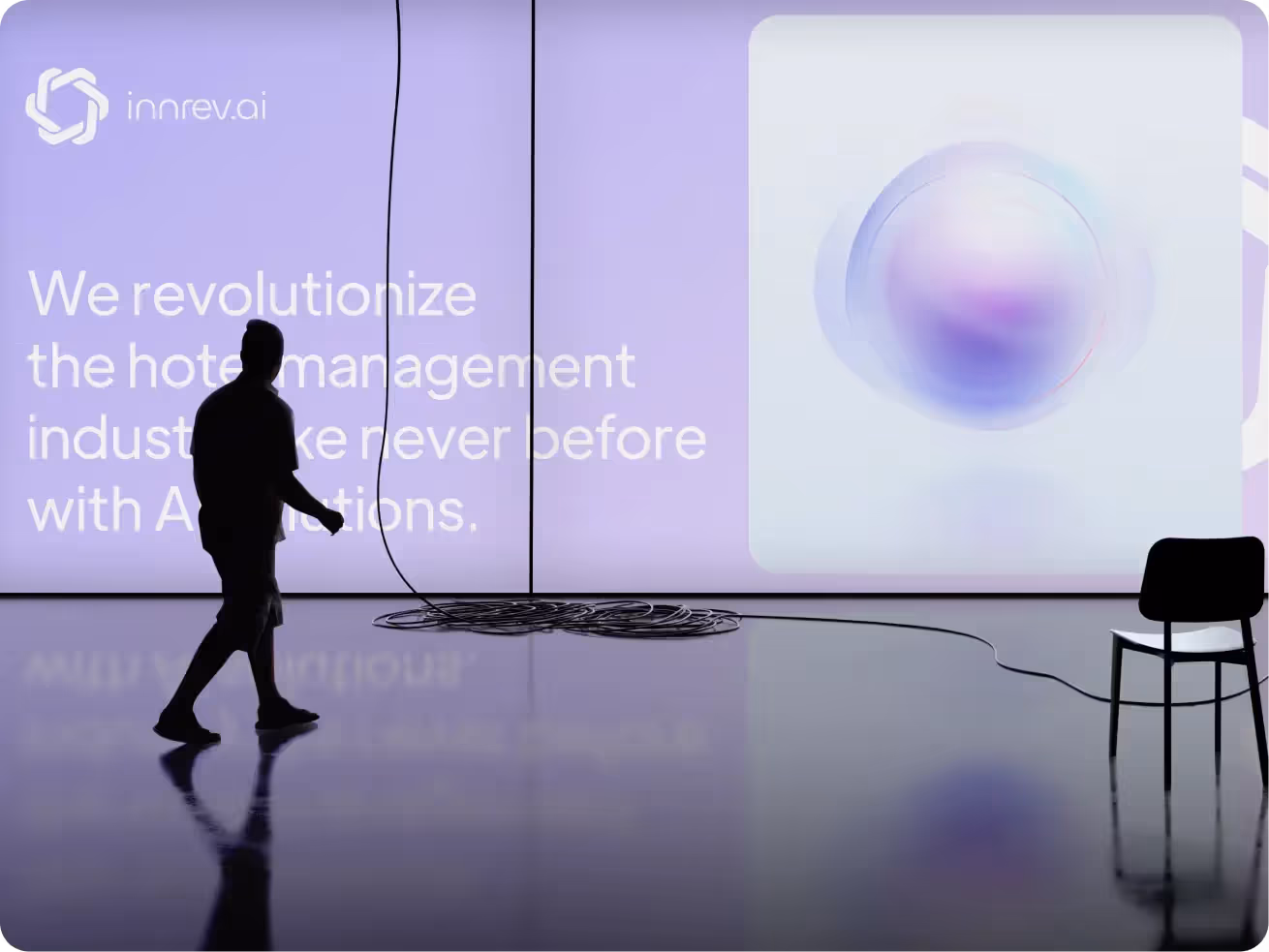 Silhouette of a person walking past a large purple screen with text about hotel management innovation. A cable coil and chair are visible, conveying a tech-focused atmosphere.