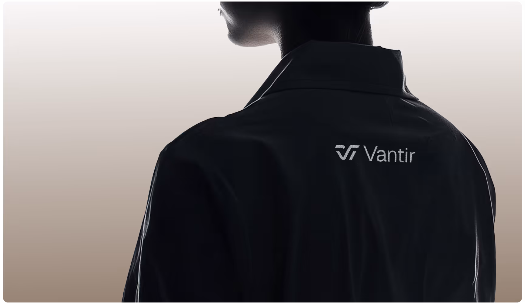 A person in silhouette wearing a dark coat with the "Vantir" logo on the back. The background is a soft gradient from cream to light brown.