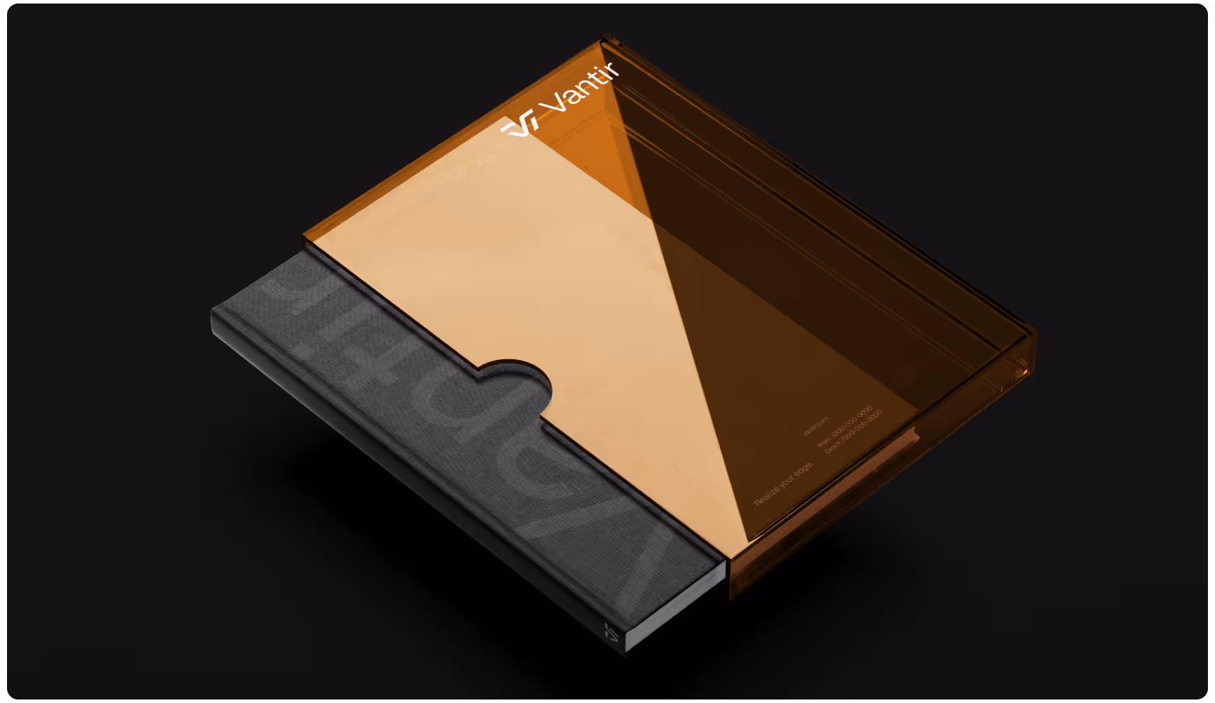 A sleek black notebook partially encased in a transparent brown cover with the text "Vantr" in the corner, set against a black background.
