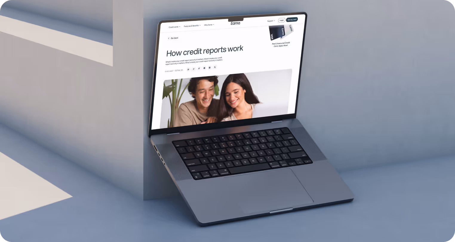 Laptop resting against a wall, displaying a webpage titled "How credit reports work" with a smiling couple in the image, conveying an informative and positive tone.