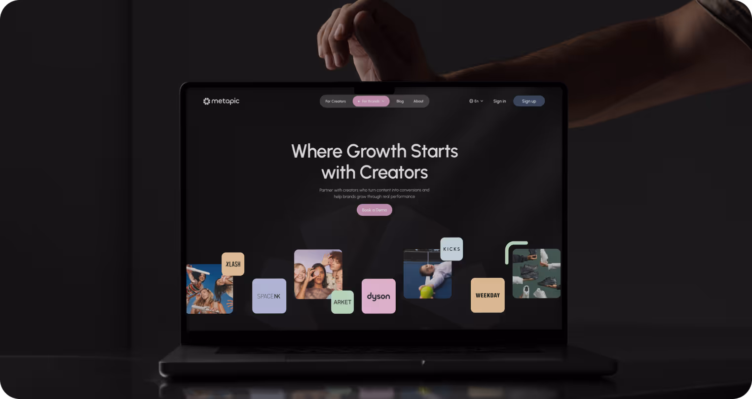 A laptop screen displays a webpage with the text "Where Growth Starts with Creators." Various brand logos and images are scattered below. A hand adjusts the laptop lid.