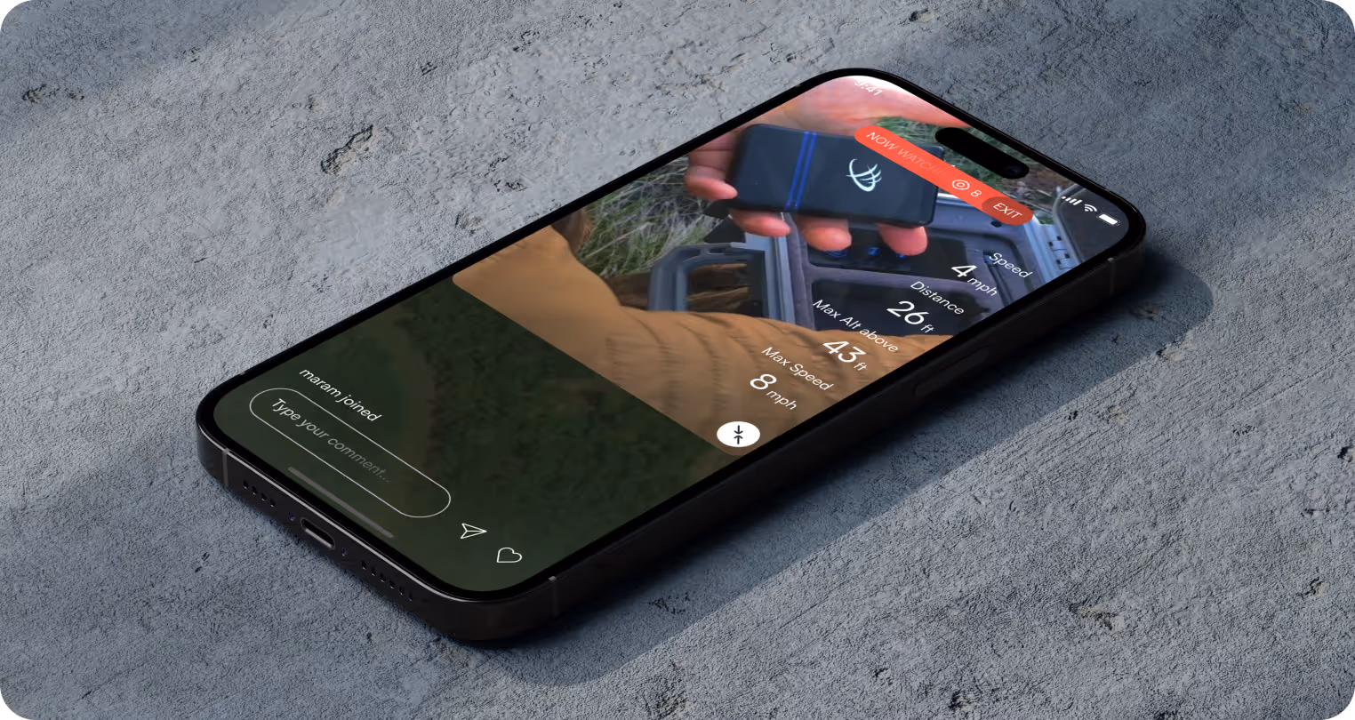 Smartphone on concrete displays an outdoors app interface with a hand holding a tool. Soft lighting, green texture, and digital elements convey adventure.