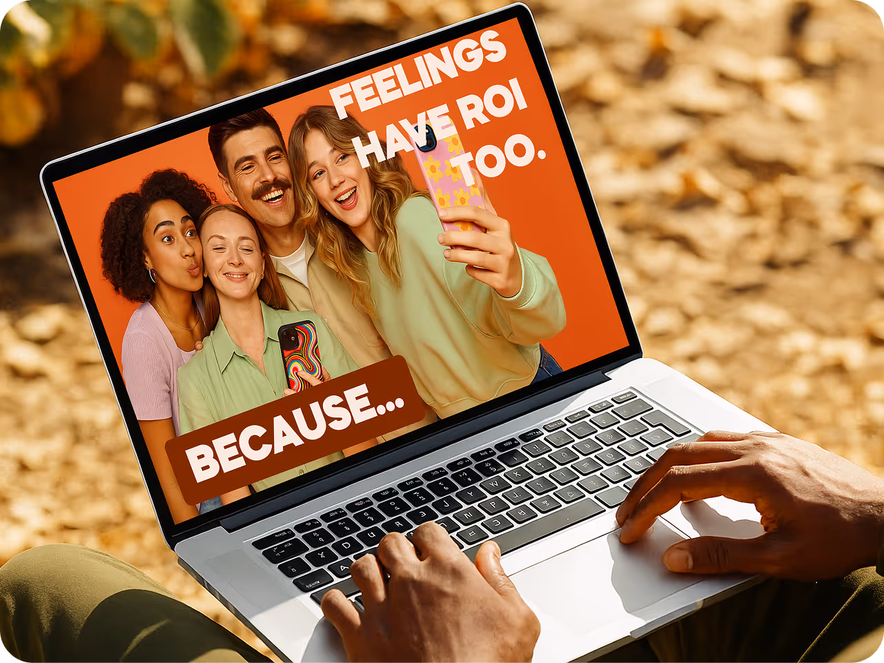 A person uses a laptop outdoors. The screen shows a diverse group of happy people taking a selfie with the text, "FEELINGS HAVE ROI TOO. BECAUSE..." on an orange background.