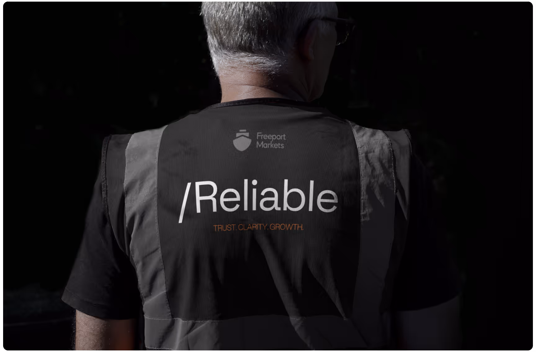 A man with gray hair, wearing a black vest. The back of the vest shows "Freeport Markets" with "Reliable" and "Trust, Clarity, Growth" in bold text.