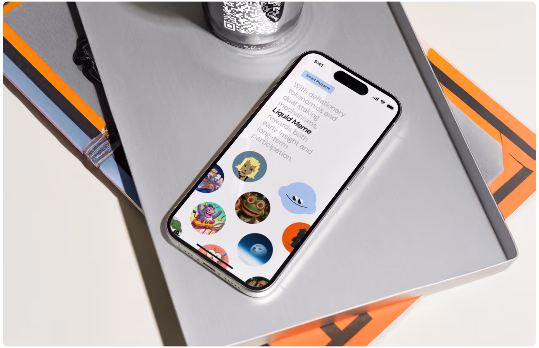 Smartphone on a gray tray displaying a colorful app with various illustrated avatars. Nearby, books and a cup with a QR code create a modern, tech-savvy vibe.