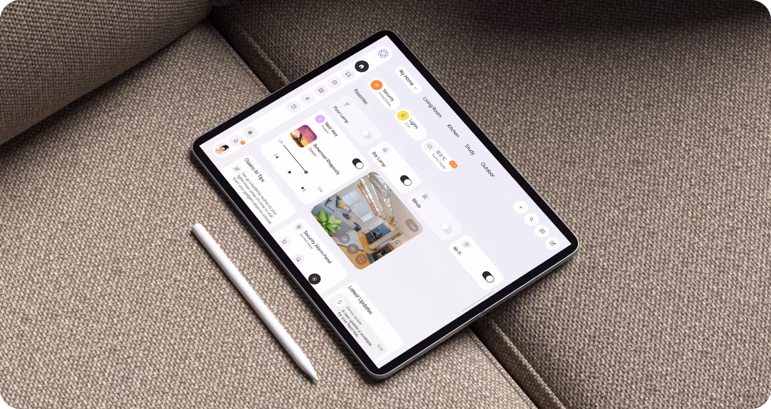 A tablet displaying a home automation app interface rests on a textured fabric sofa. A stylus lies beside it, suggesting a seamless tech lifestyle.