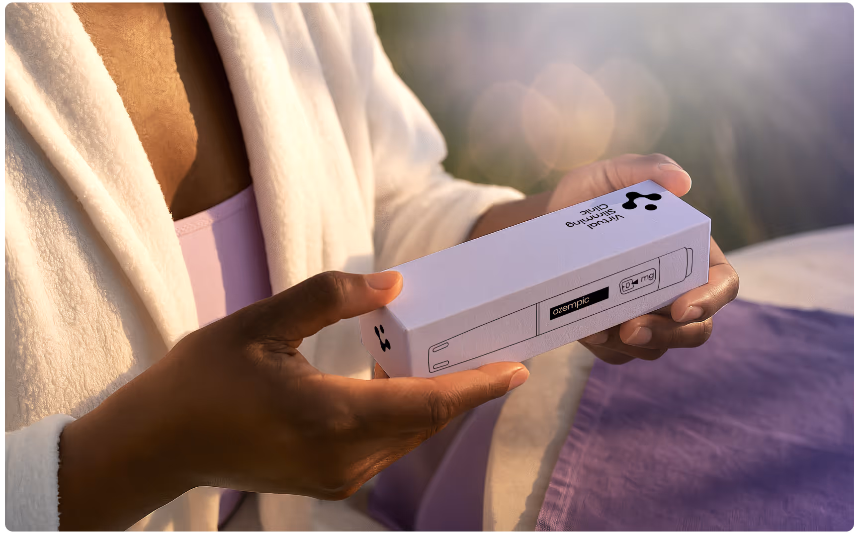 A person in a white robe holds a white box labeled "Liquid Carmine" with a serene, outdoor background. The mood is peaceful and reflective.