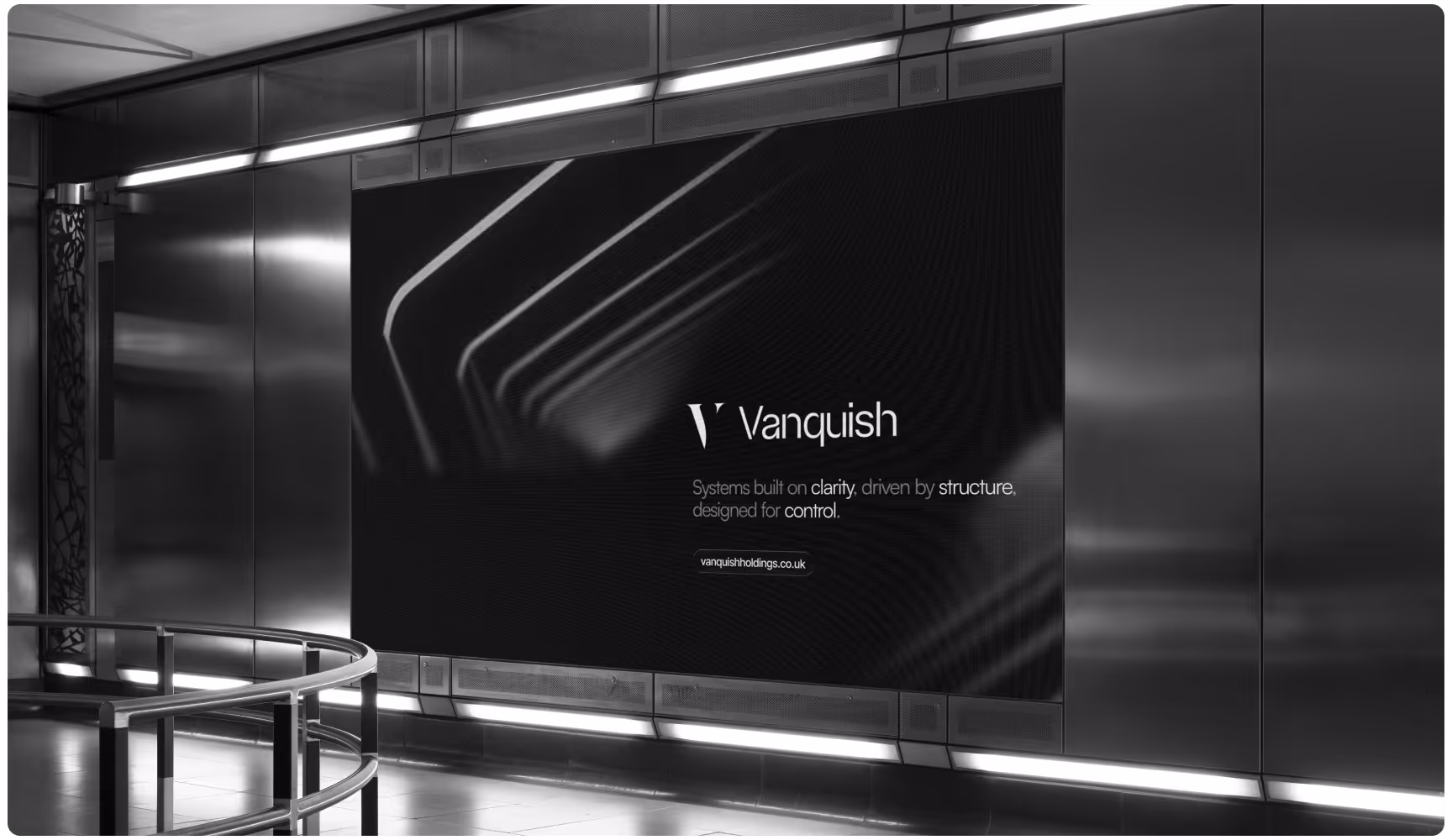 A sleek, modern advertisement in a metallic subway station with the text "Vanquish" and a tagline about clarity and structure on a dark background.