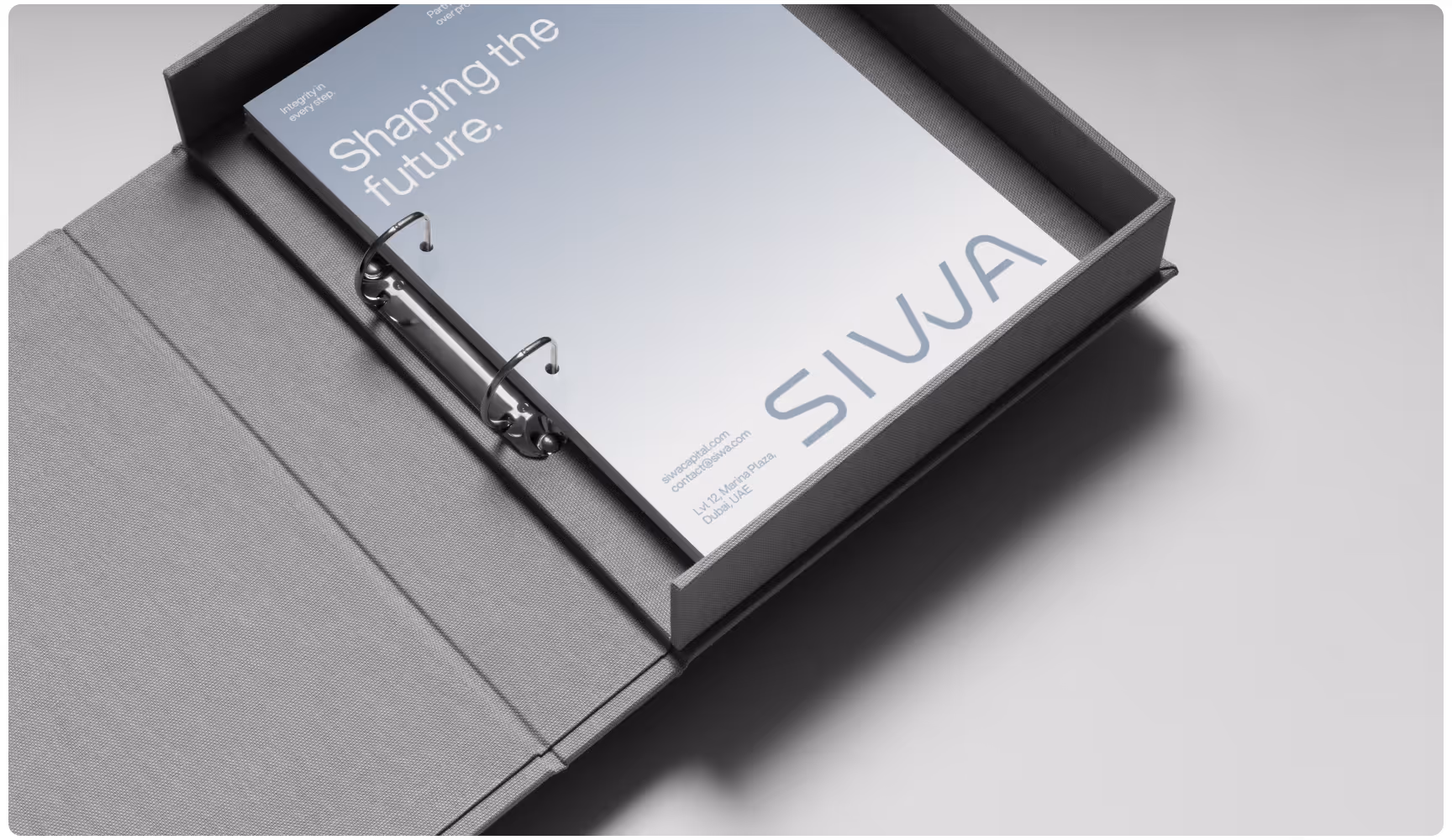Open gray binder with metal rings holds a minimalist document titled "Shaping the Future." The setting is clean and professional.
