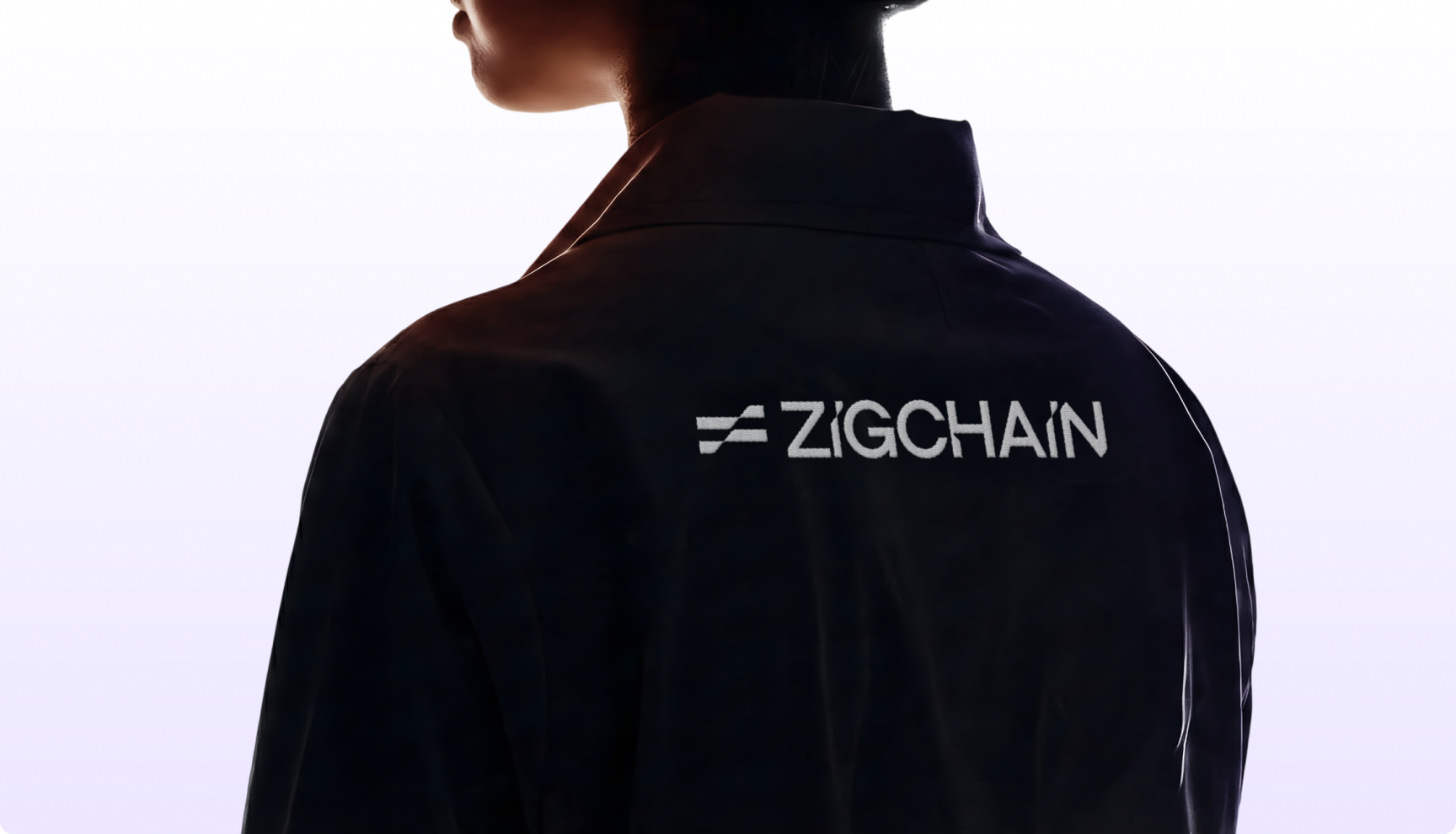 A person with short hair is shown from behind in a dark jacket with "ZIGCHAIN" printed on it. The background is a soft gradient from light purple to white.