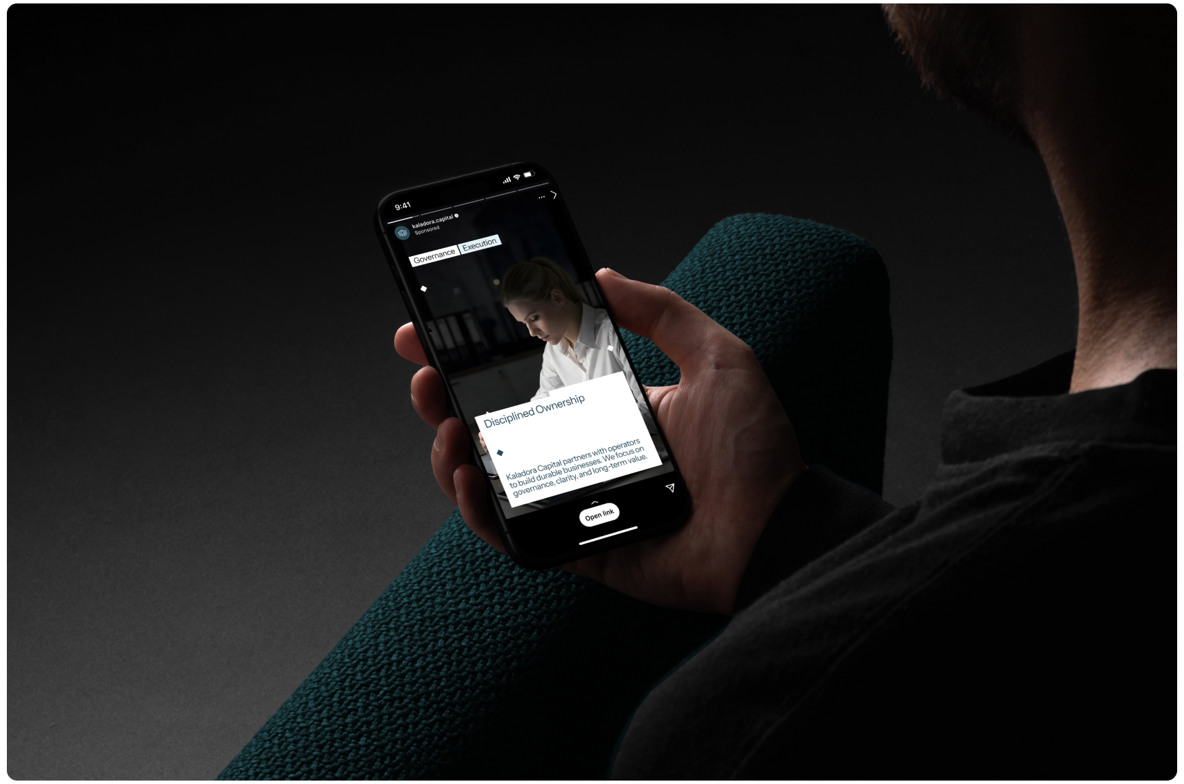 A person holds a smartphone displaying a news article in a dimly lit setting. The screen shows an image of a focused individual reading. The mood is calm and contemplative.