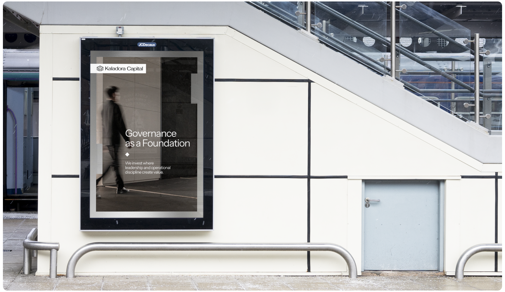 Large poster on a modern building exterior features a blurred person walking. Text reads "Governance as a Foundation" in a sleek, professional font.