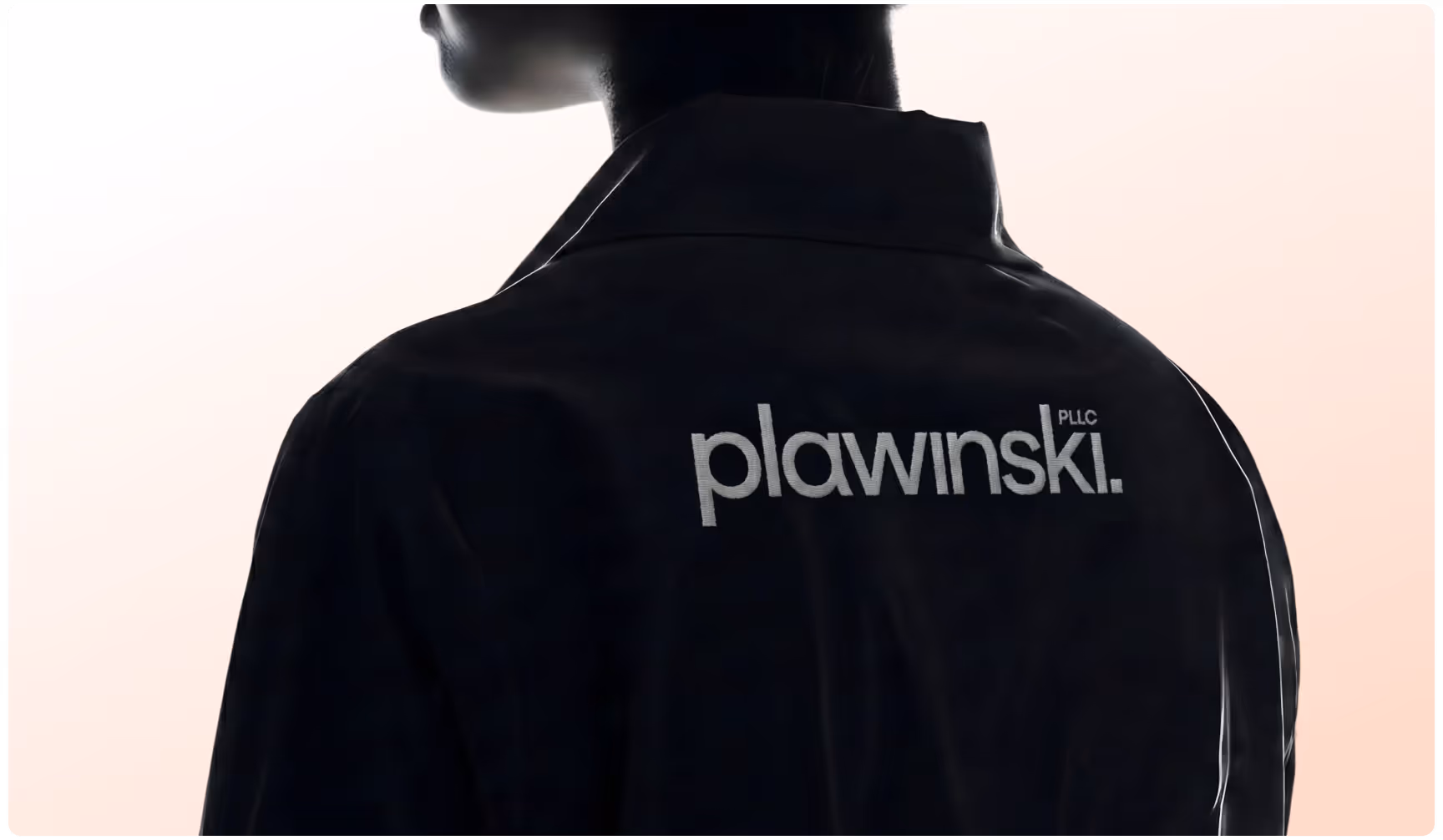 Close-up of a black jacket embroidered with the Plawinski PLLC logo on the back, showcasing minimalist legal branding, premium corporate apparel, and modern law firm identity design.