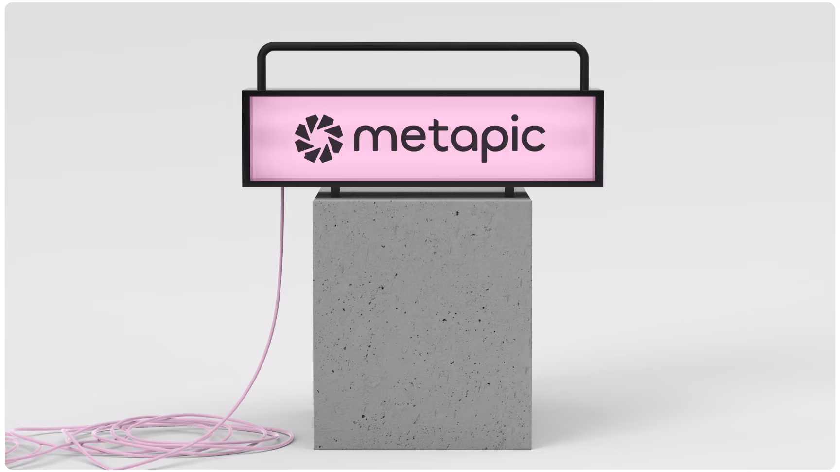 A illuminated pink sign with black framing displaying the "metapic" logo, mounted on a concrete block against a plain grey background with a coiled pink power cord attached.