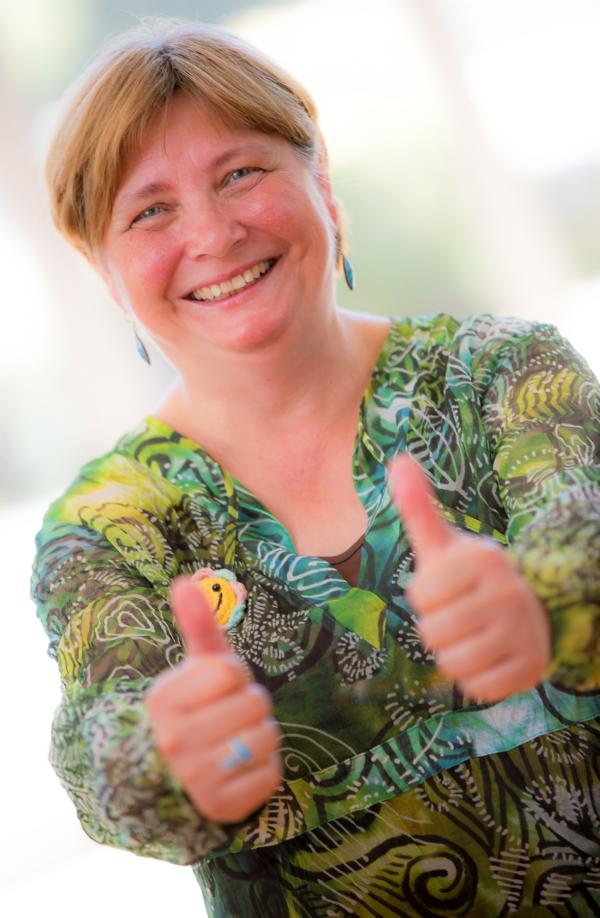 Frau die beide Daumen nach oben zeigt und lacht