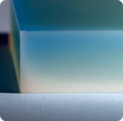 Close-up of a translucent gradient block with blue and green hues on a textured surface.