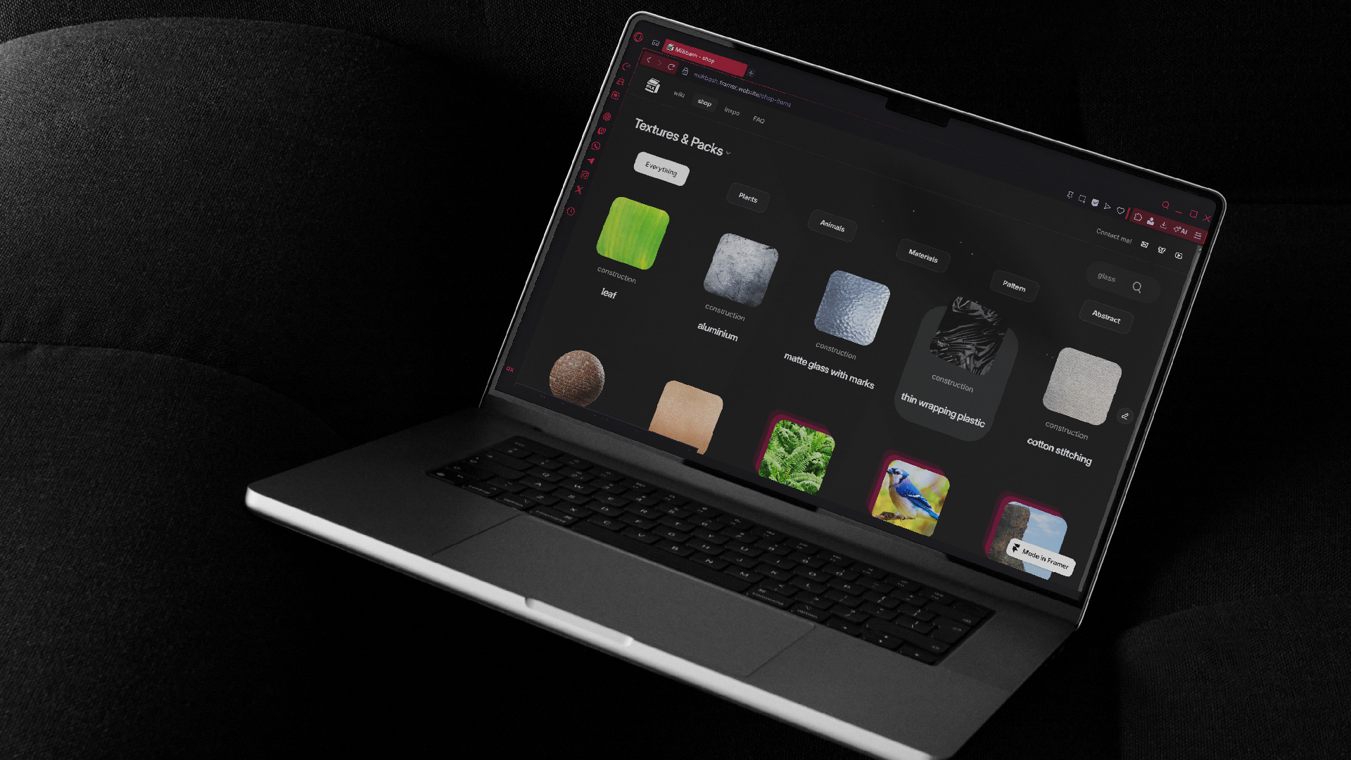 laptop mockup including an open navigator showcasing a dark-styled website with shop items within