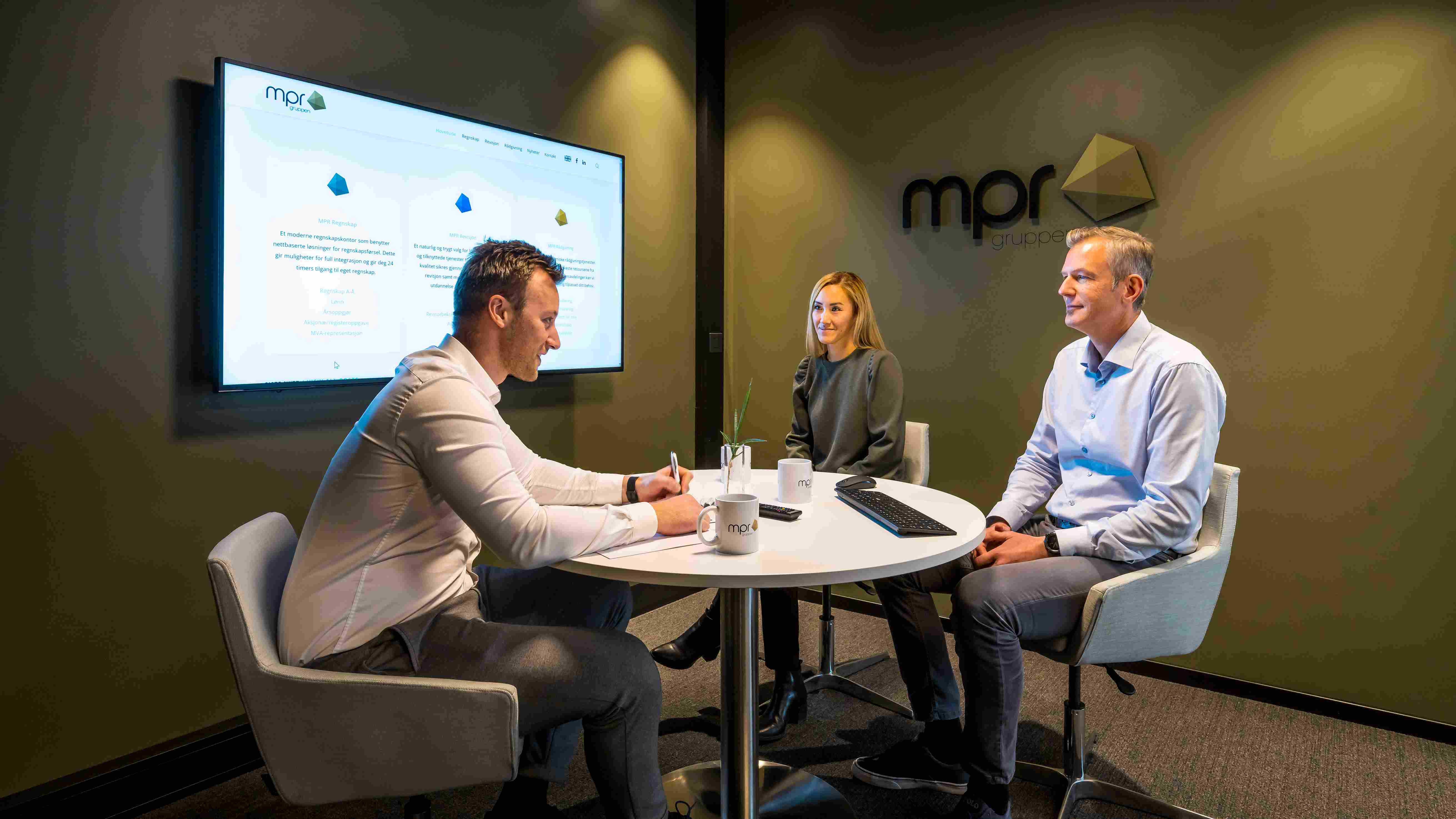 Kontorlokale hos MPR Revisjon, din pålitelige partner innen revisjon i Oslo, med ansatte i hyggelig samtale i et moderne møterom.