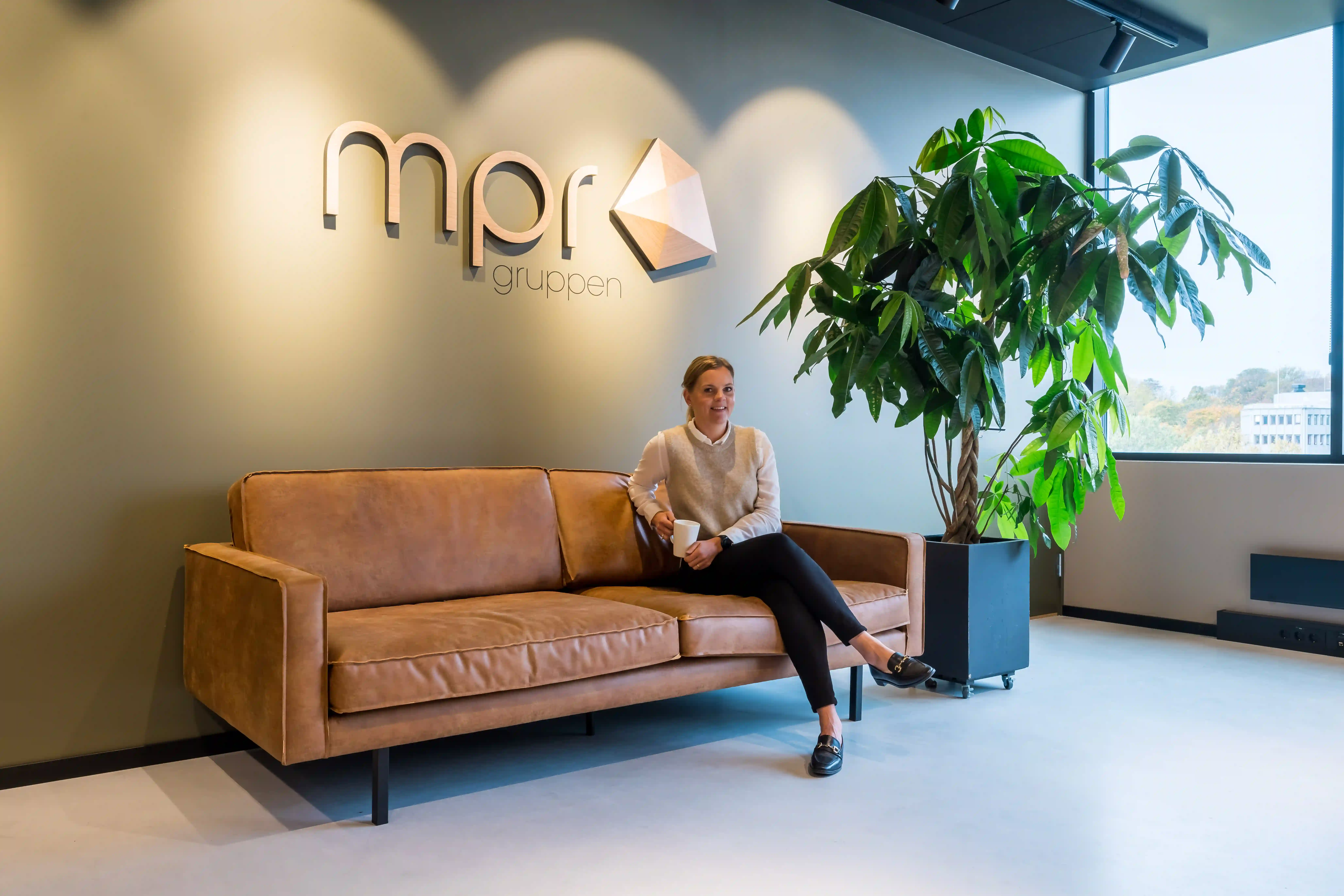 En regnskapsfører hos MPR Regnskap sitter i sofaen på deres kontorer i Oslo med nærhet til Bærum