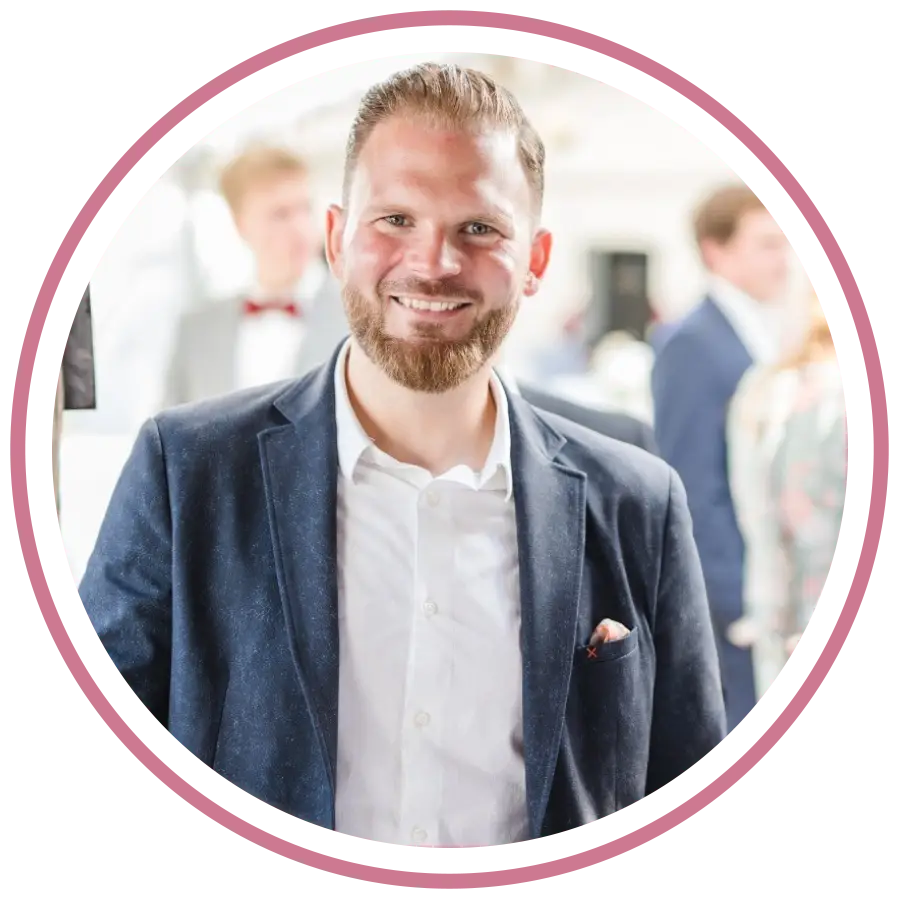 „Porträtfoto von Cassandra Schwerter, Gründerin von Sent4Souls - CSG Projects, mit pink-violetten Haaren und schwarzer Bluse. Sie steht auf einer Dachterrasse vor moderner Architektur, lehnt sich lächelnd an ein Geländer.