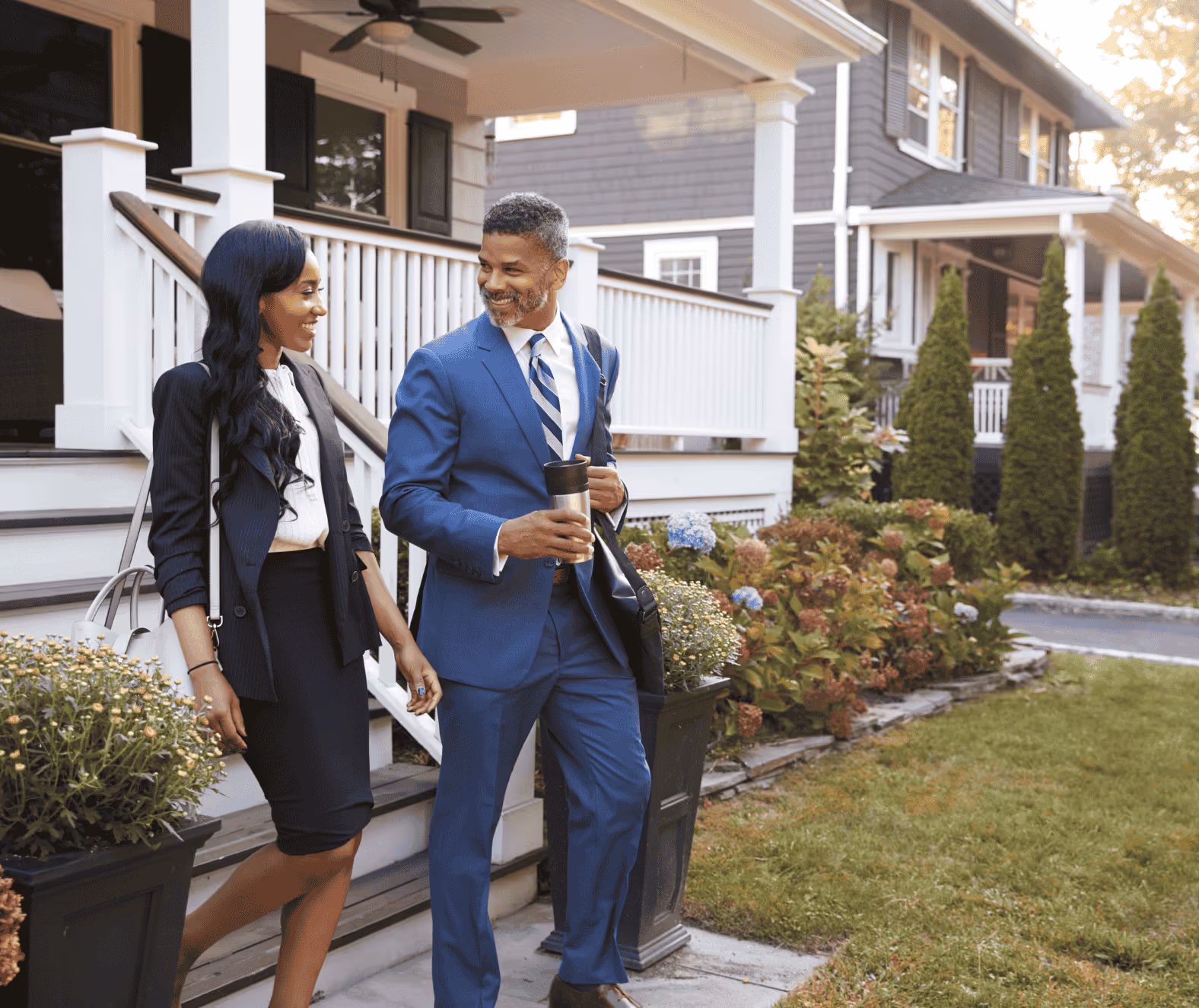 Professional couple smiling and walking together outside a suburban home.