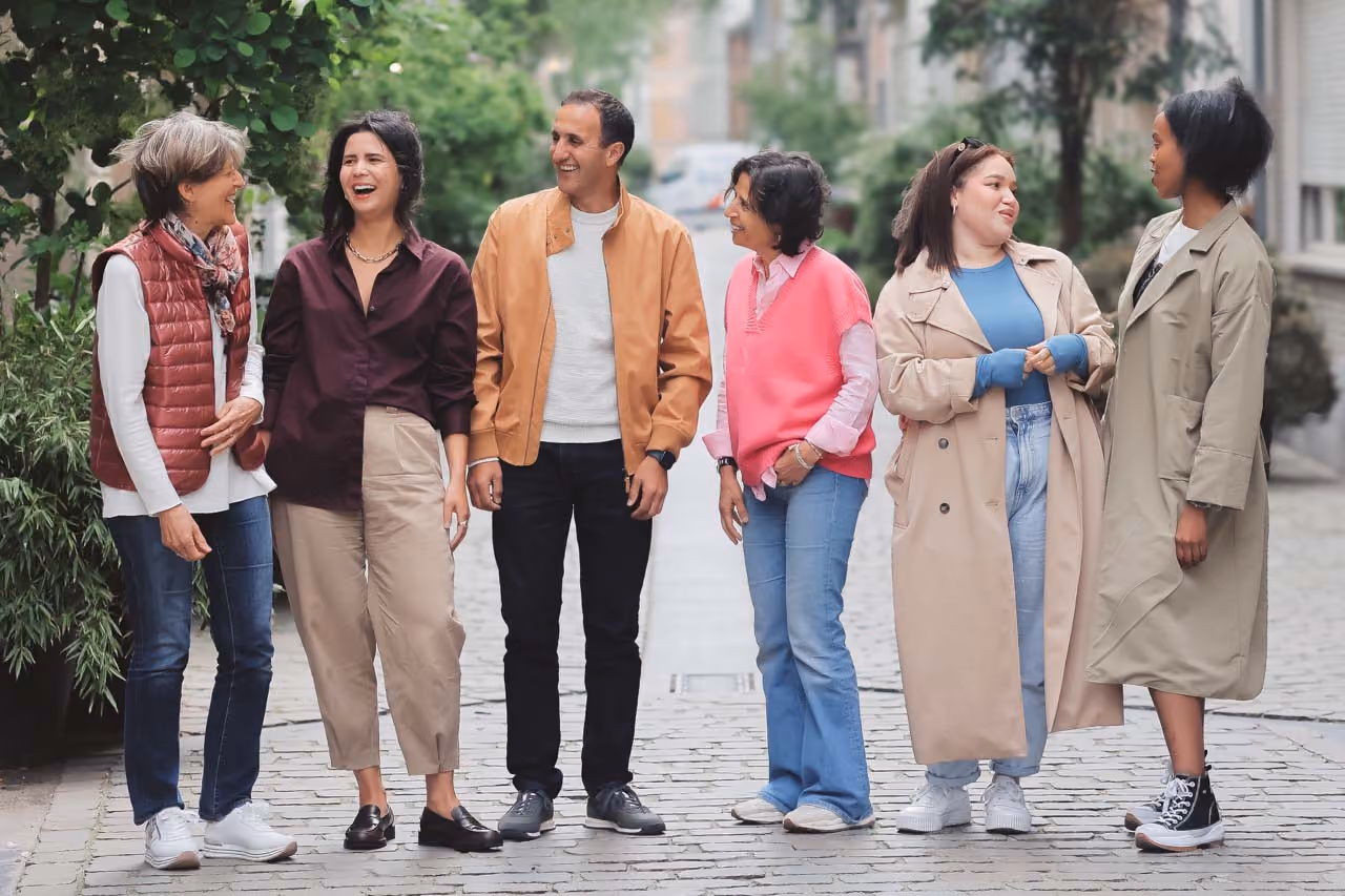 Groupe de personnes de profils variés (d'âge et d'origine différents) discutant dans une ruelle ensoleillée