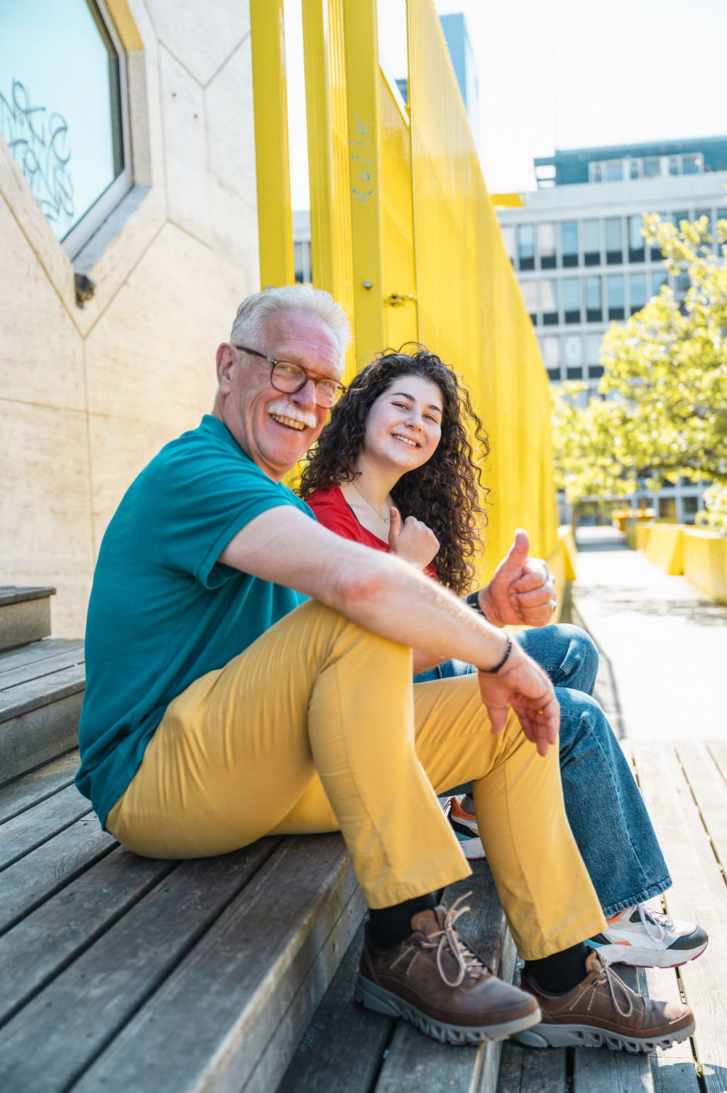 Une jeune femme avec de longs cheveux bruns sourit de toutes ses dents avec sa mentor à côté d'elle qui sourti également. La mentor est une femme âgée avec des cheveux blancs et des lunettes.
