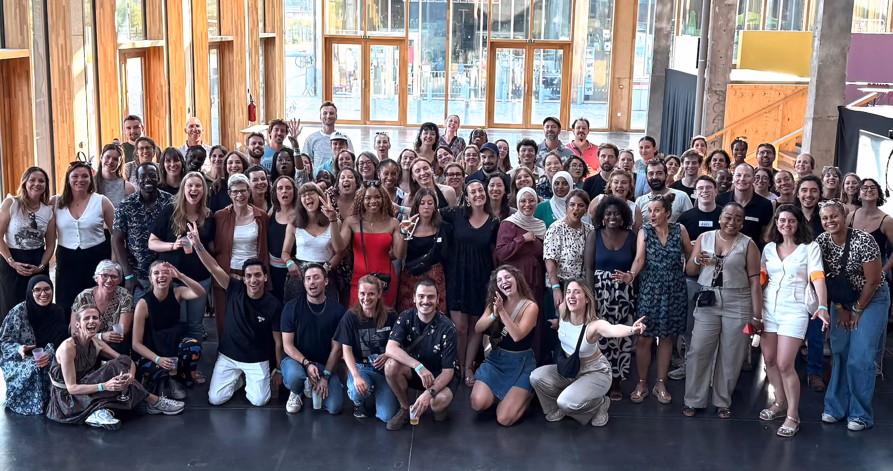 Photo de l'équipe de DUO Anvers, un groupe de personnes le long d'un mur extérieur qui se sourient et rigolent ensemble