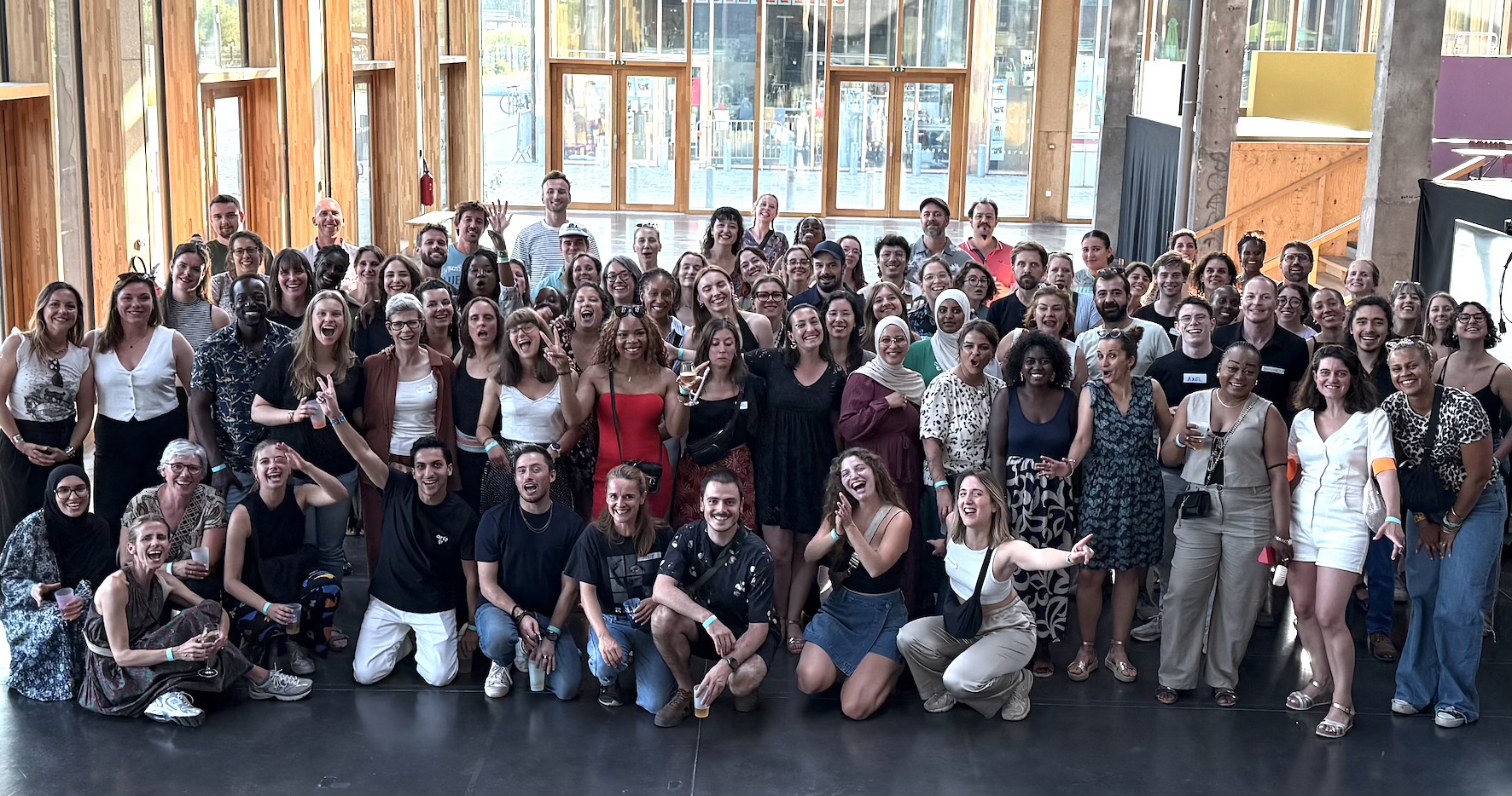 Photo de l'équipe de DUO Anvers, un groupe de personnes le long d'un mur extérieur qui se sourient et rigolent ensemble