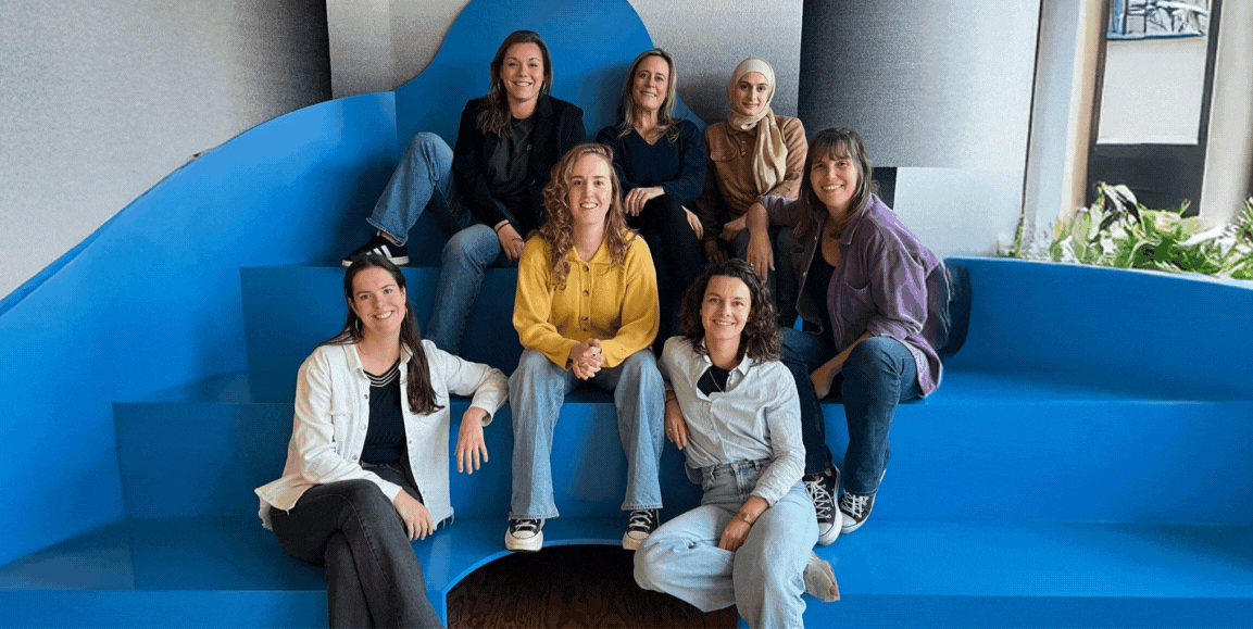 Photo de l'équipe de DUO Anvers, un groupe de personnes le long d'un mur extérieur qui se sourient et rigolent ensemble