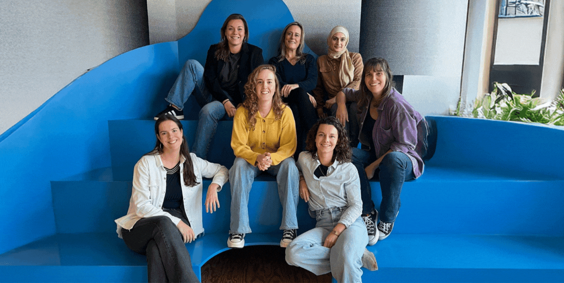 Photo de l'équipe de DUO Anvers, un groupe de personnes le long d'un mur extérieur qui se sourient et rigolent ensemble