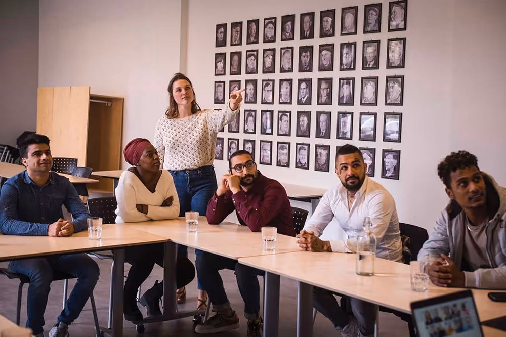 Un groupe de jeunes regardent dans la même direction en suivant une séance d'information chez DUO for a JOB