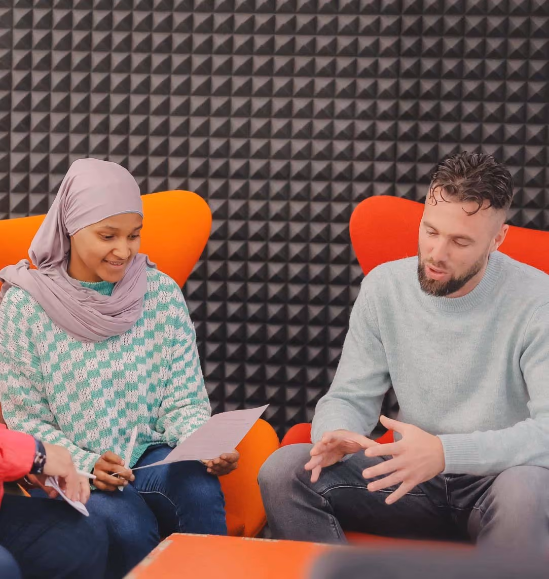 Une jeune femme voilée est assise à côté d'un coordinateur DUO, il lui explique le programme