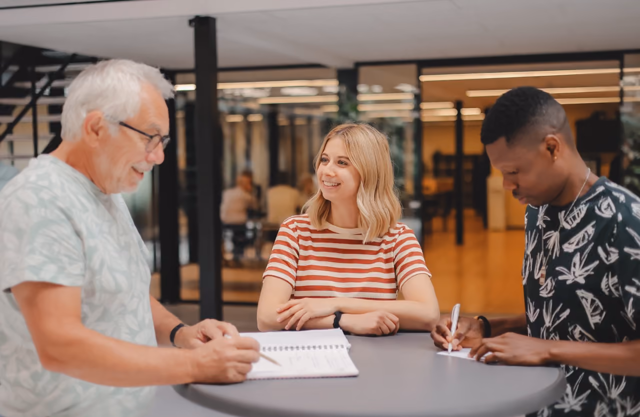 Une coordinatrice regardant avec bienveillance un duo de mentee et mentor signant leur convention pour commencer le programme de DUO for a JOB