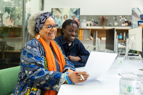 Une jeune femme avec un grand sourire est assise à côté d'un mentor avec des petits lunettes argentées