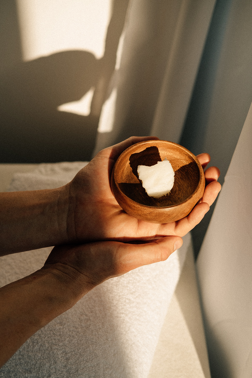 Zwei Hände halten eine Schale mit Kokosnussöl.