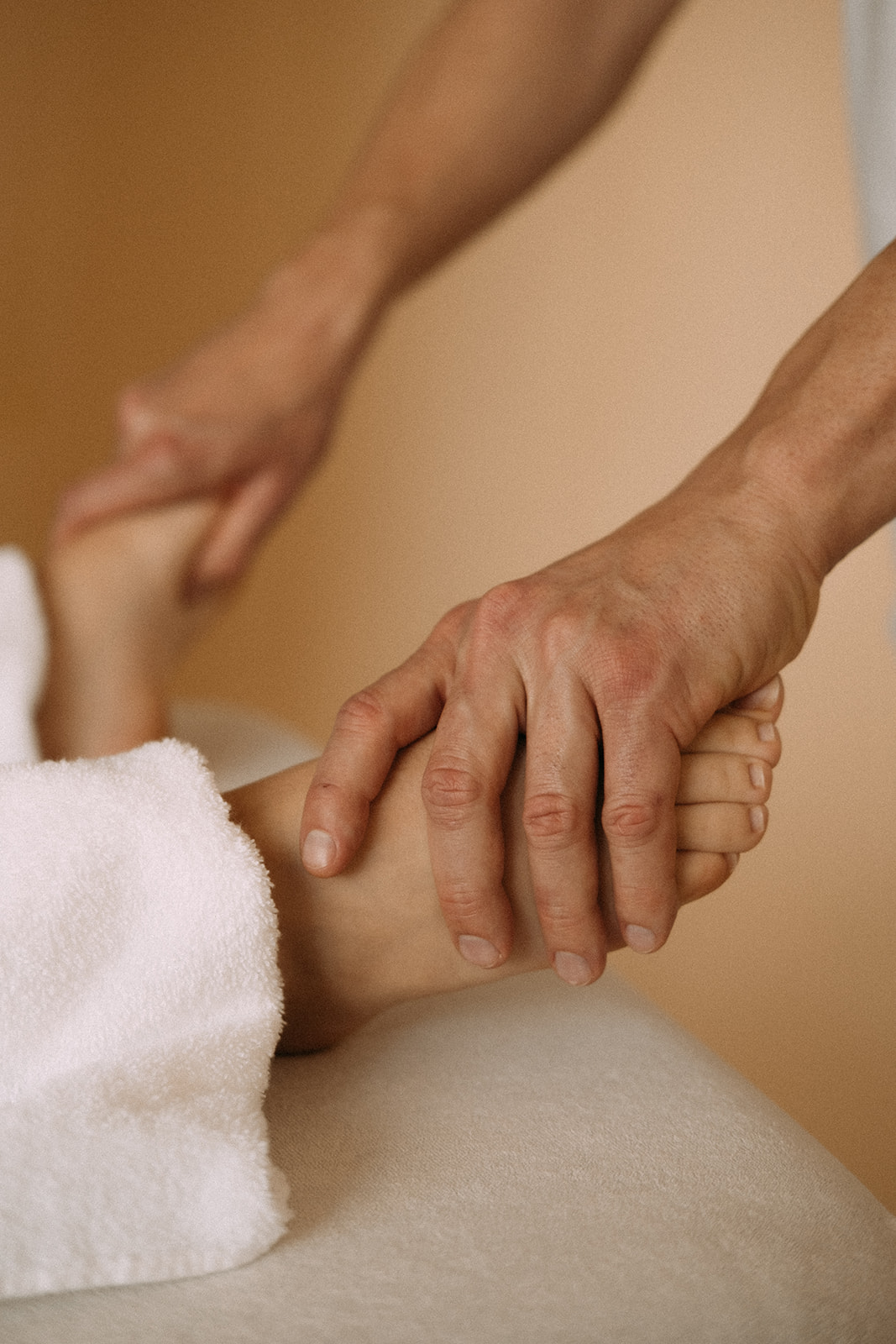 Der Masseur massiert mit beiden Händen die Füsse der Patientin.