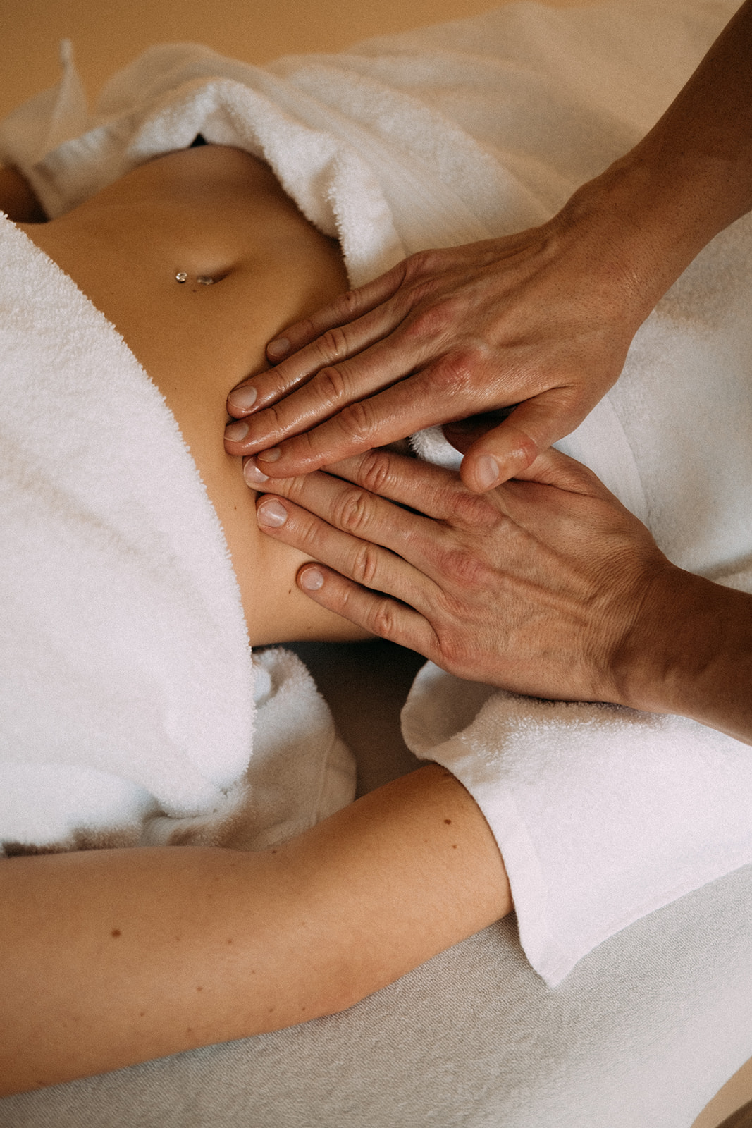 Der Masseur massiert mit beiden Händen den seitlichen Bauchbereich einer Patientin.