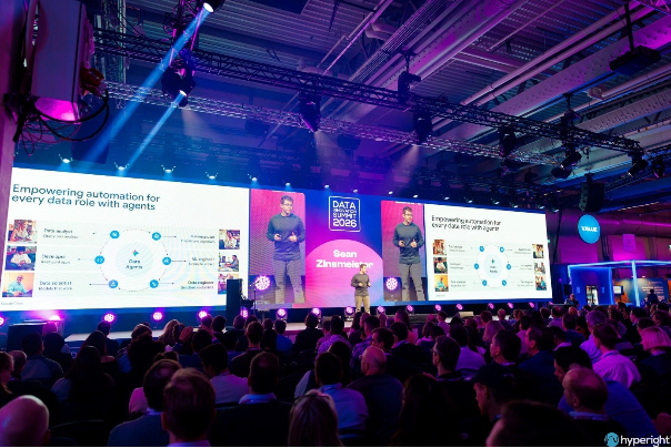 A person standing in front of a large screen with a crowd of peopleAI-generated content may be incorrect.