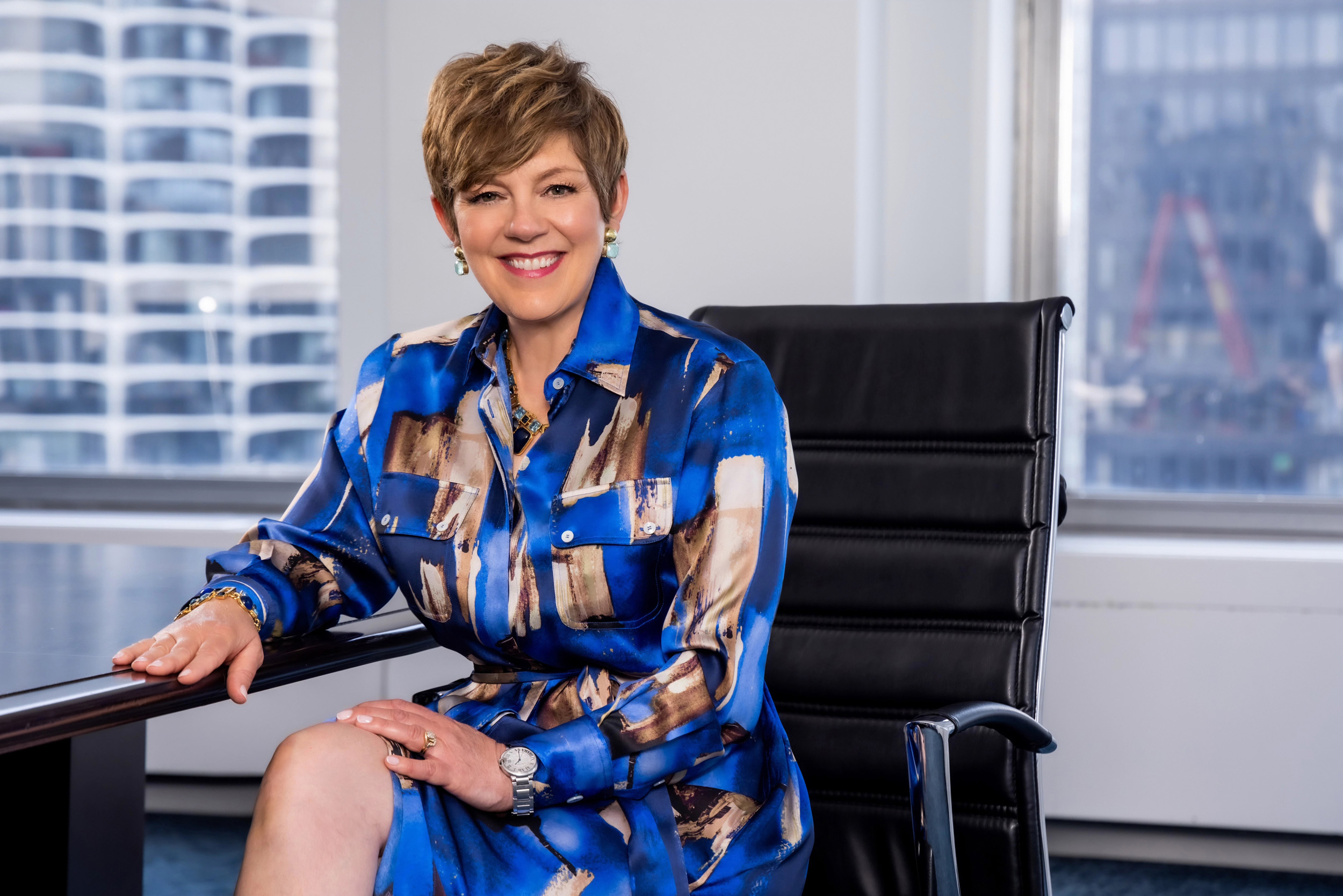 Dr. Victoria Medvec, a middle-aged woman with short brown hair, smiles while seated at the head of a conference table.