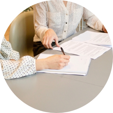 Two people signing paperwork in a business setting.